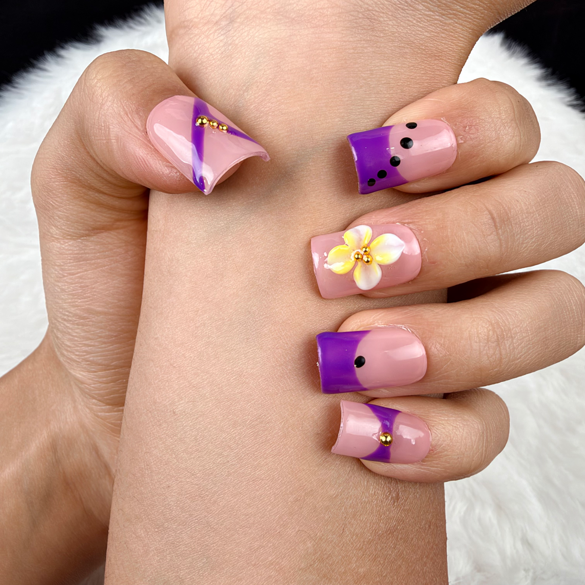 Detail shot of Violet Ribbon purple and yellow floral square press-on nails on hand
