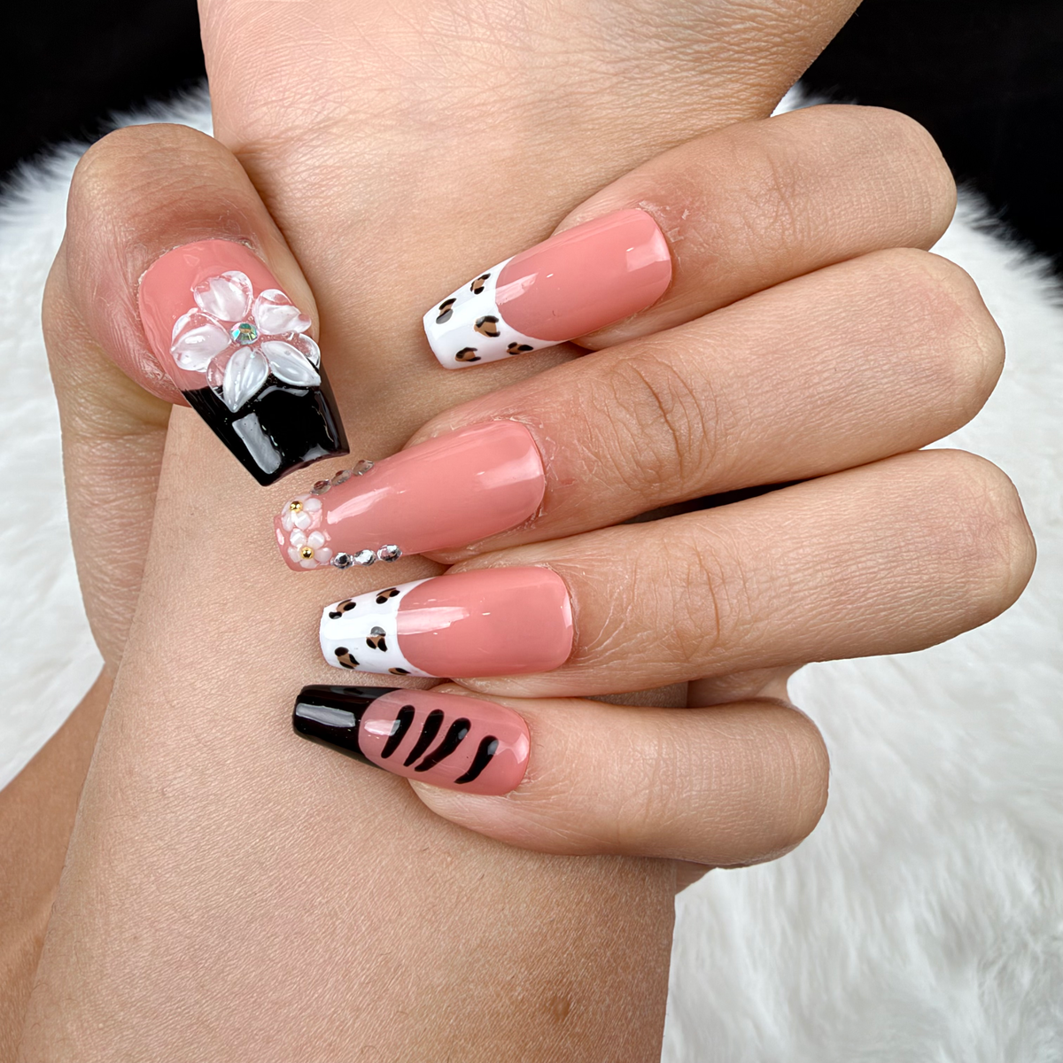 Detail shot of Noir Bouquet black French tip and pale pink floral square press-on nails on hand