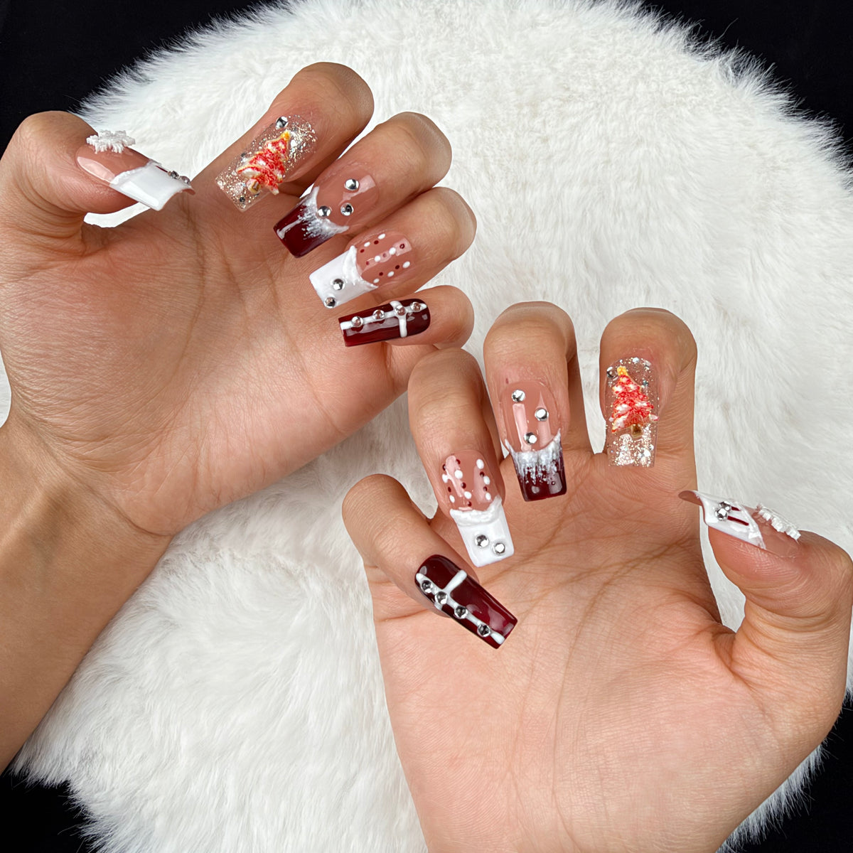 Close-up of hands wearing Winter Rose burgundy glitter and white snowflake Christmas square press-on nails