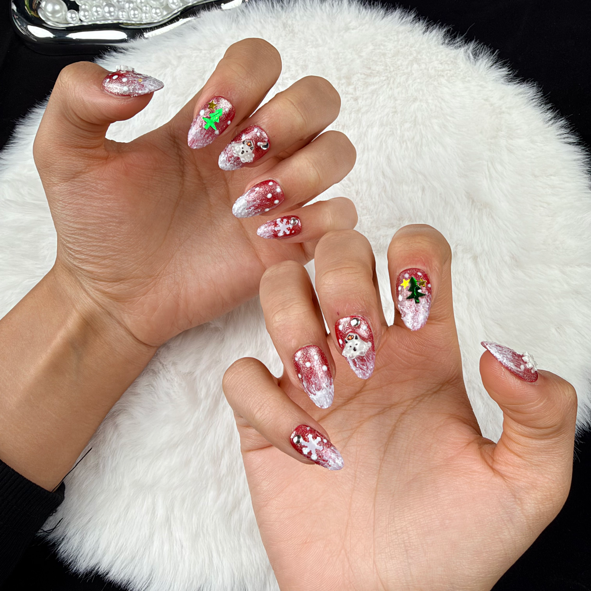 Hands wearing Frosted Holiday rose glitter Christmas almond press-on nails with snowflakes