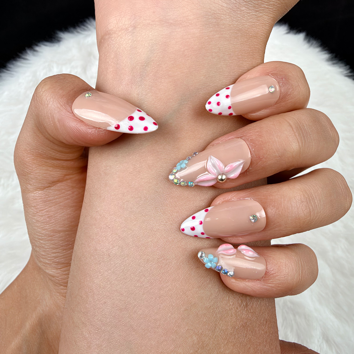 Detail shot of Blush Garland pink polka dot French tip floral almond press-on nails on hand