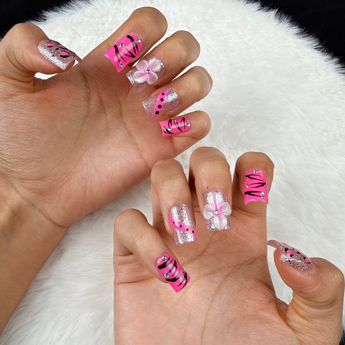 Close-up of hands wearing Pink Spark hot pink, black and silver floral square press-on nails