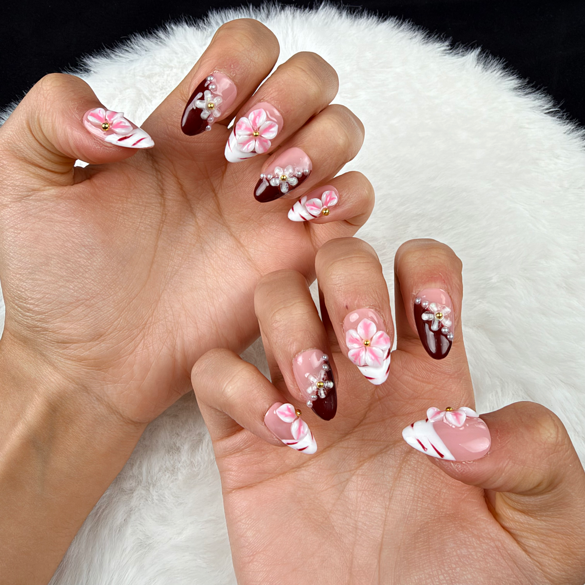Close-up of hands wearing Rose Marble pink floral and burgundy French tip almond press-on nails