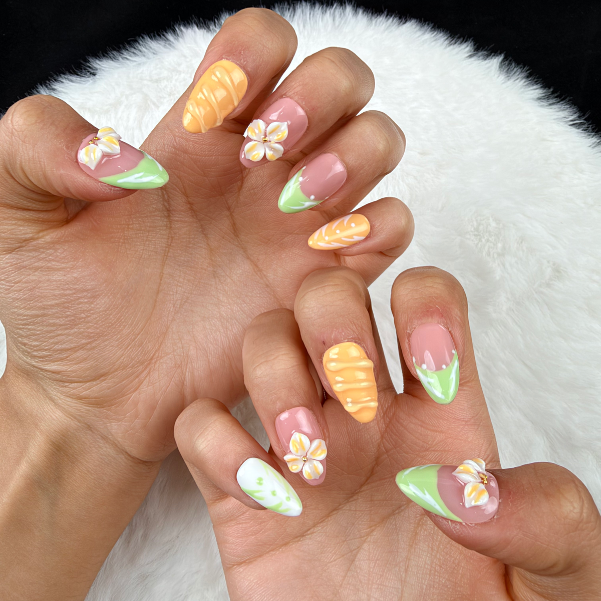 Close-up of hands wearing Citrus Blossom mint, pink and orange floral almond press-on nails