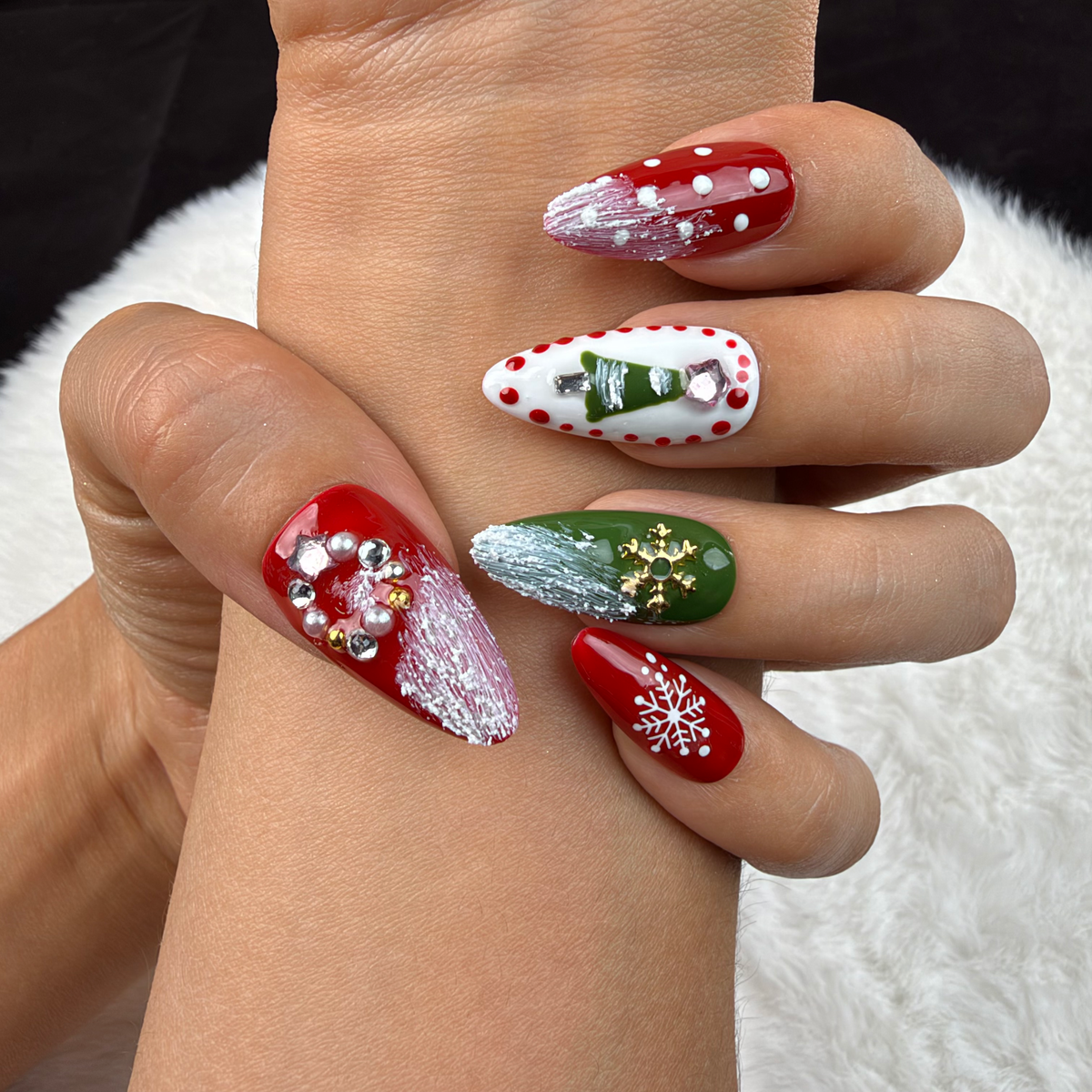 Close-up of hands wearing Festive Garland red, green and white Christmas almond press-on nails with wreaths and snowflakes