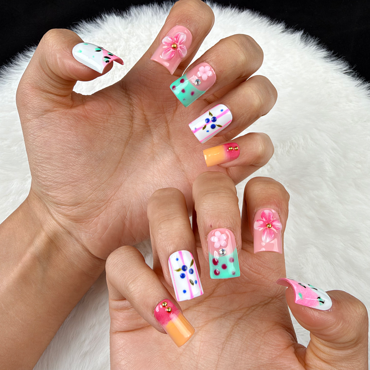 Close-up of hands wearing Pastel Flower Mix pink, mint and blue floral square press-on nails