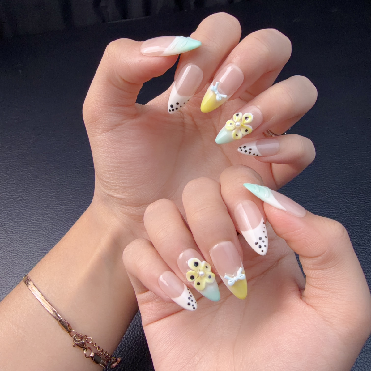 Hands wearing Mint, butter yellow and white pastel floral French tip almond press-on nails