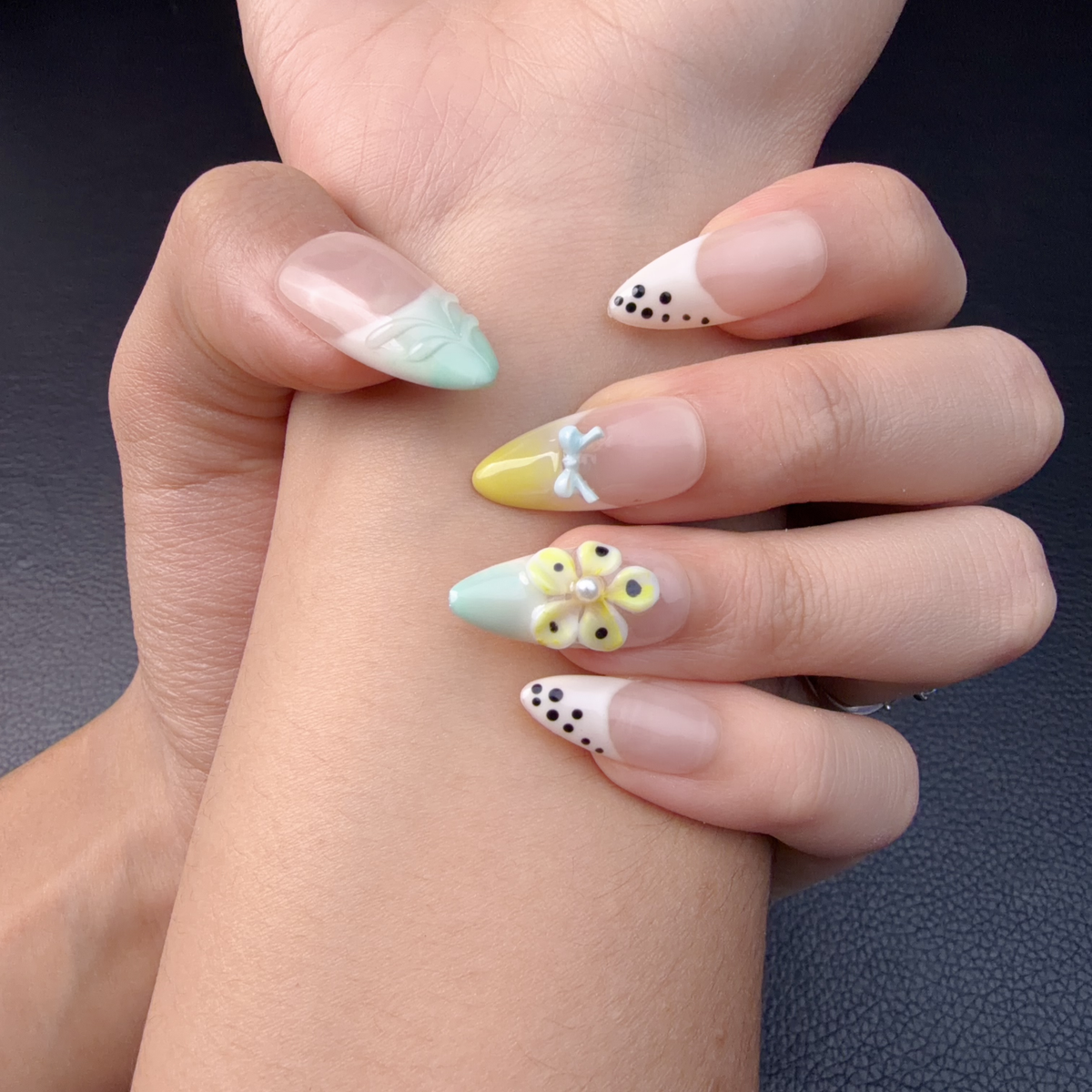 Hands wearing Mint, butter yellow and white pastel floral French tip almond press-on nails