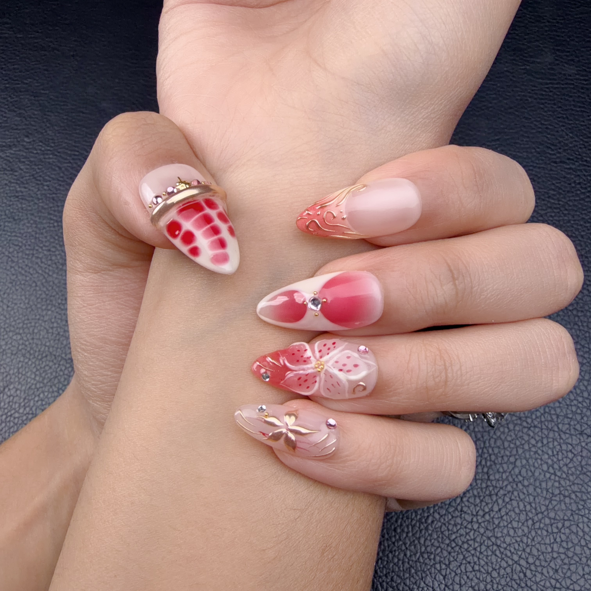Hands wearing Strawberry Bloom nude pink and berry red floral medium almond press-on nails