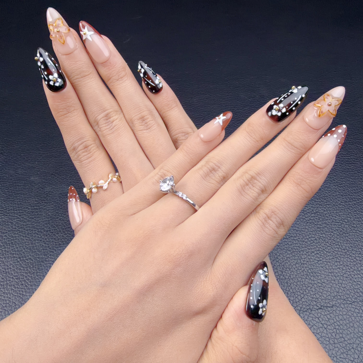 Hands wearing Cherry Noir espresso brown and caramel floral almond press-on nails