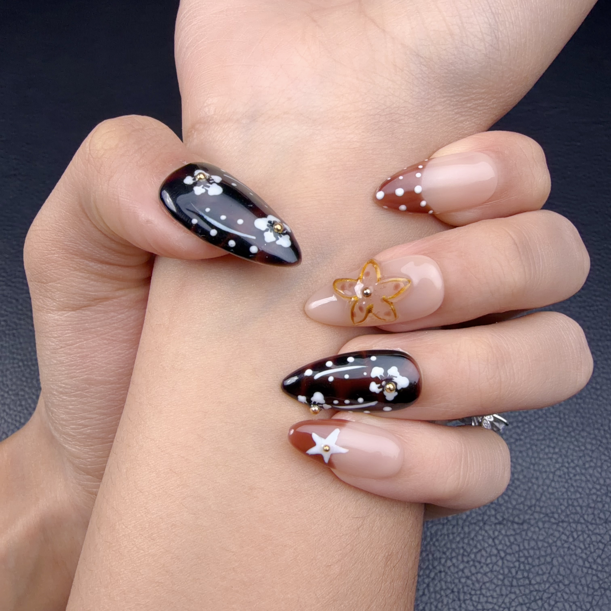 Hands wearing Cherry Noir espresso brown and caramel floral almond press-on nails