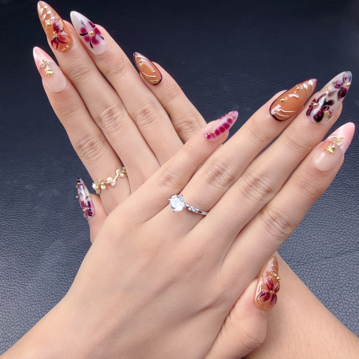 Hands wearing Autumn Petals amber, blush pink and wine red floral almond press-on nails