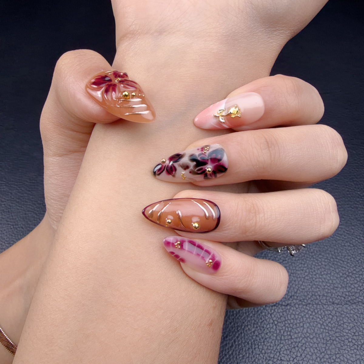 Hands wearing Autumn Petals amber, blush pink and wine red floral almond press-on nails