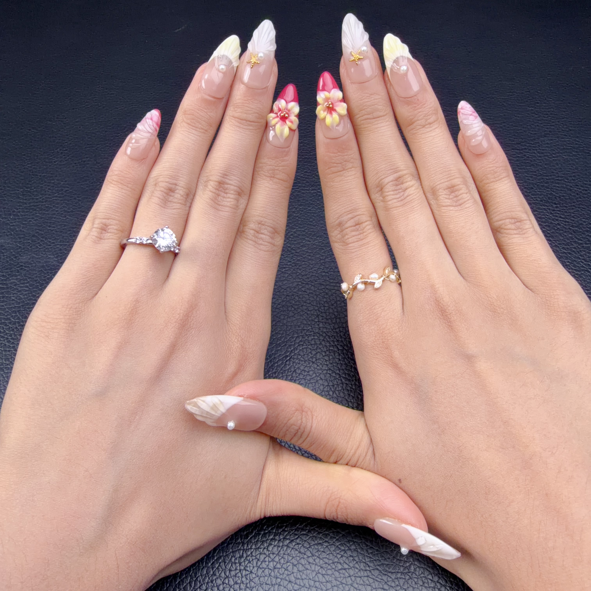 Hands wearing Pink 3D floral seashell medium almond press-on nails with pearls and gold starfish