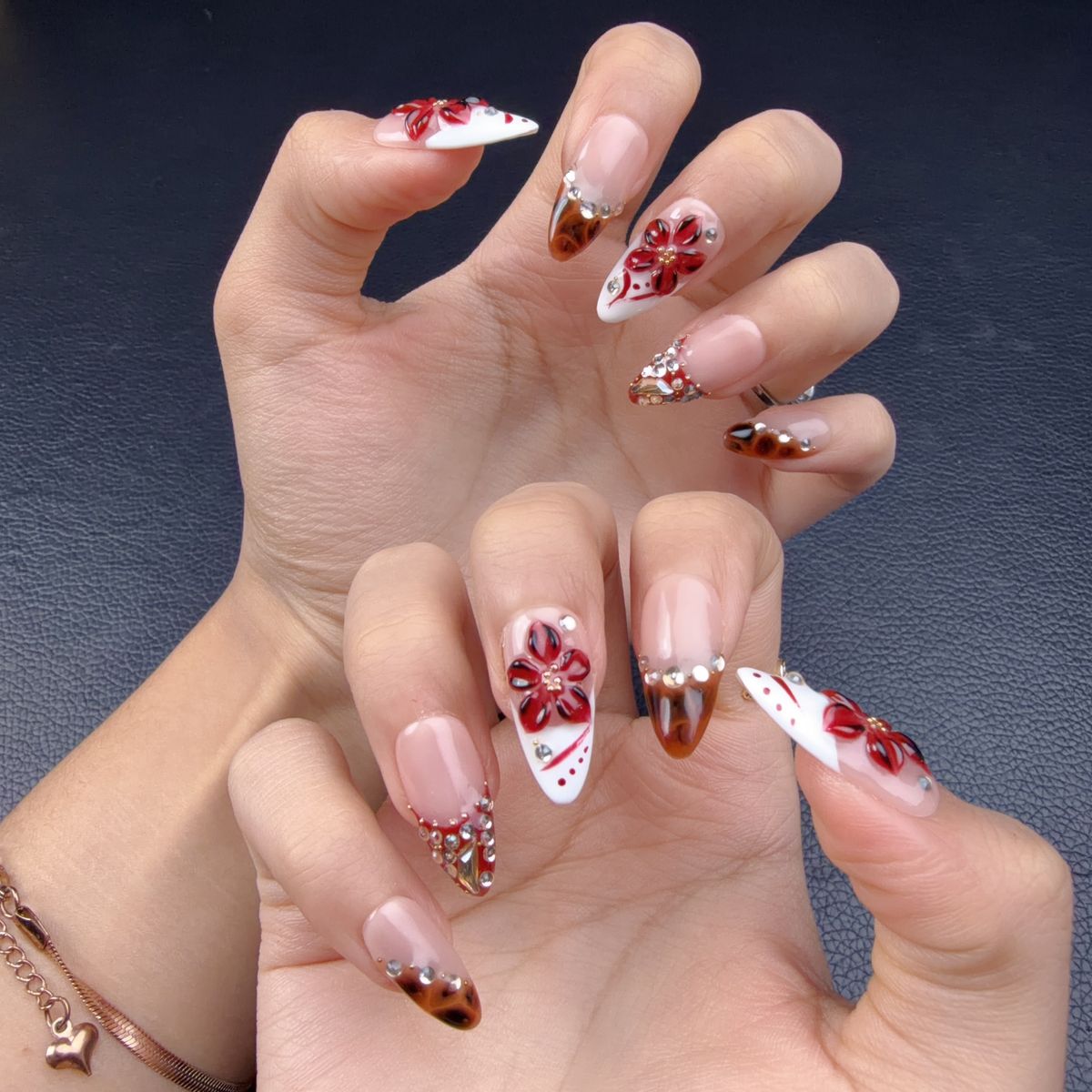 Hands wearing Red French tip floral tortoiseshell stiletto press-on nails