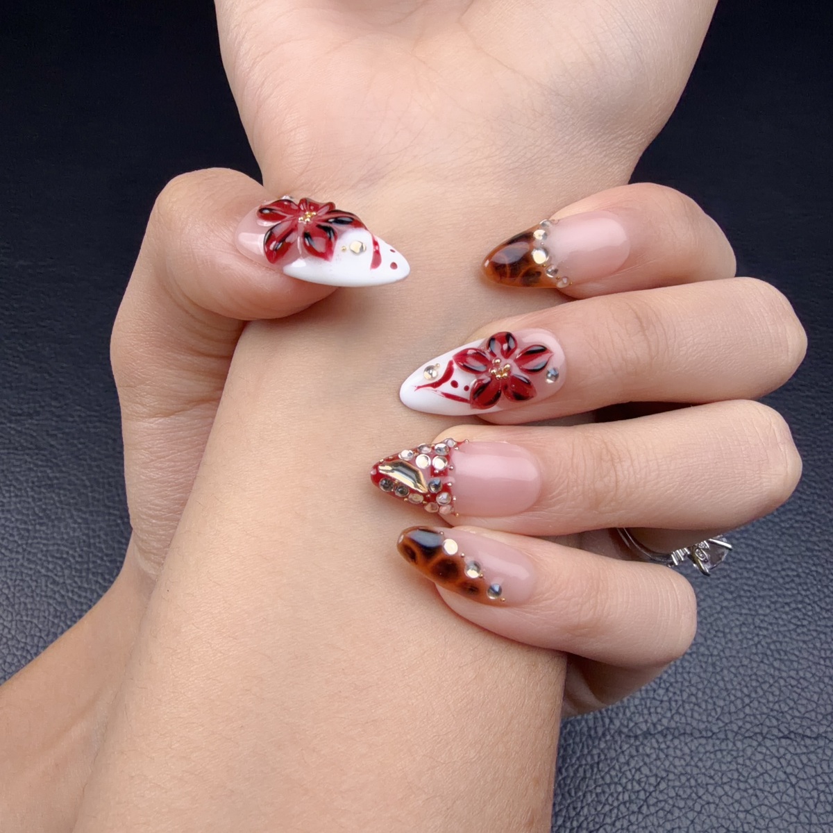 Hands wearing Red French tip floral tortoiseshell stiletto press-on nails
