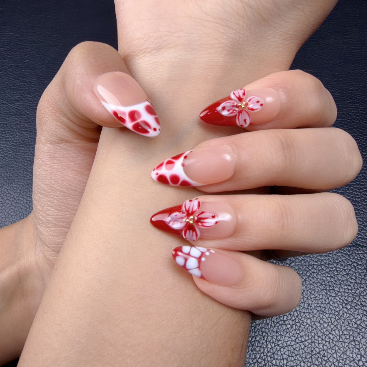 Hands wearing Scarlet Bloom red and white 3D floral medium almond press-on nails