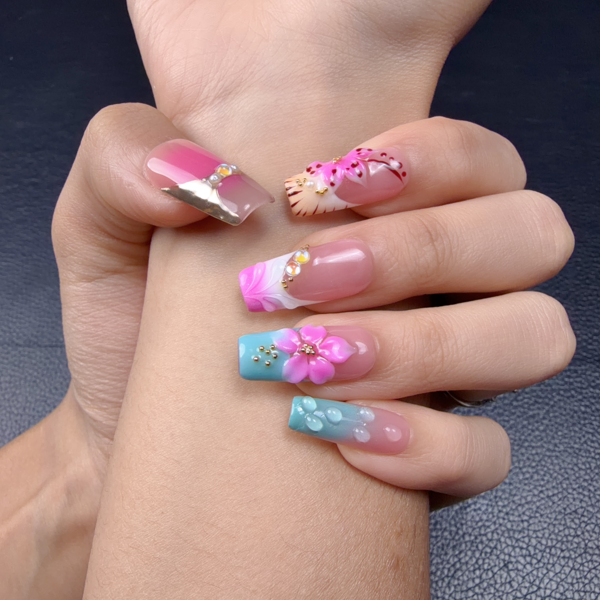 Hands wearing Candy Garden pink and aqua blue 3D floral long square press-on nails