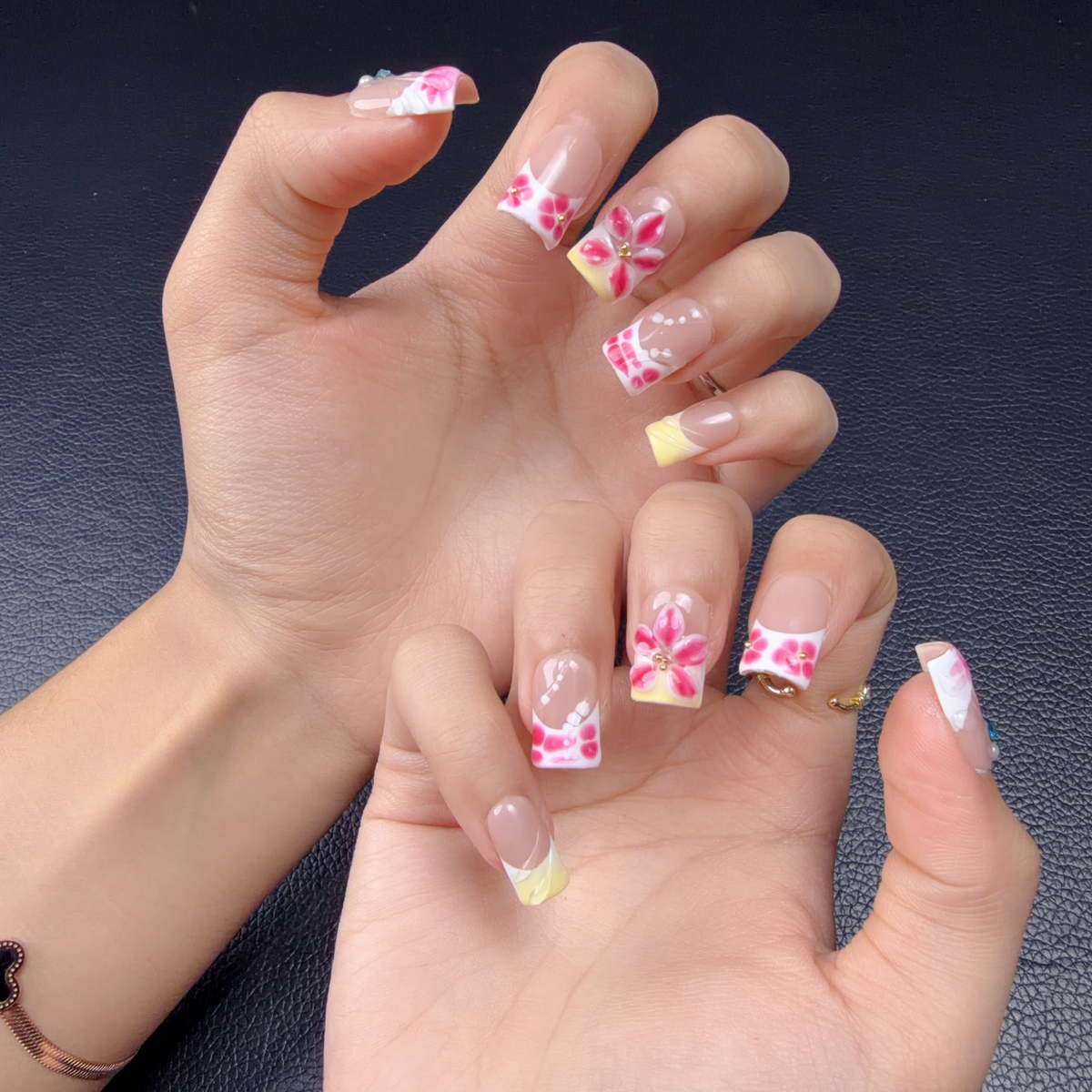 Hands wearing Pink heart graphic floral almond press-on nails with yellow French accents
