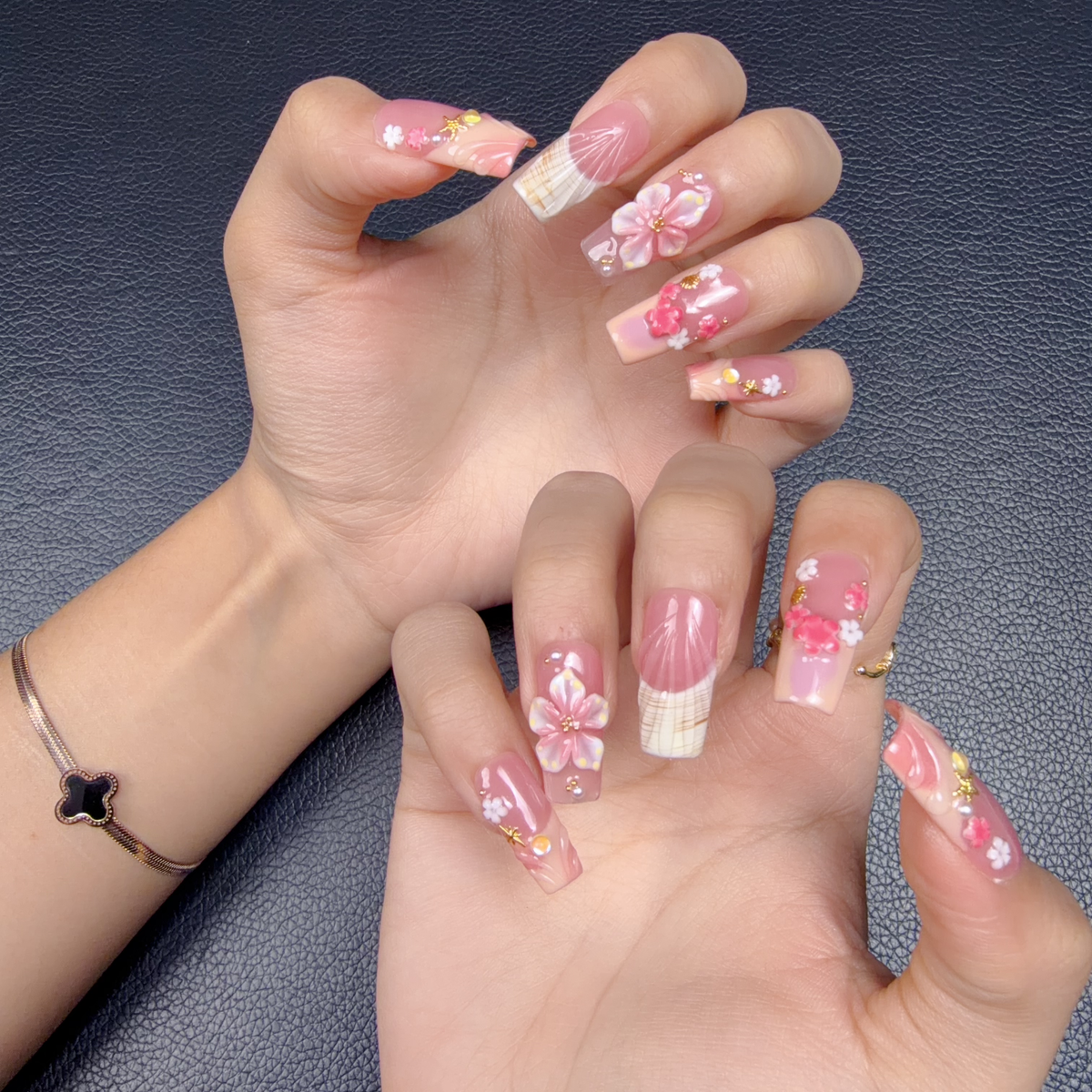 Hands wearing Lily Blush pink 3D floral square press-on nails with pearls and gold accents