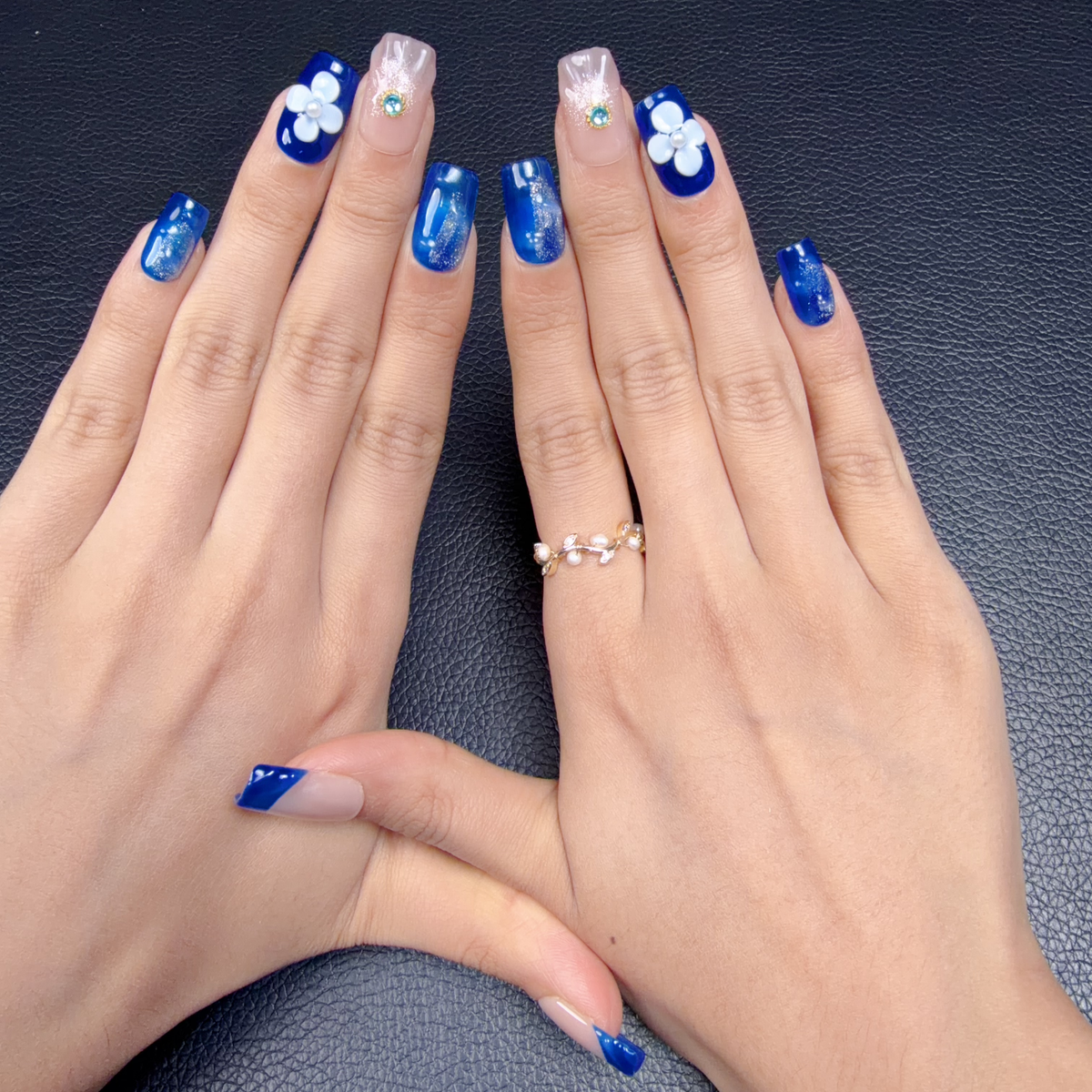 Hands wearing Cobalt blue 3D floral medium square press-on nails with white flowers