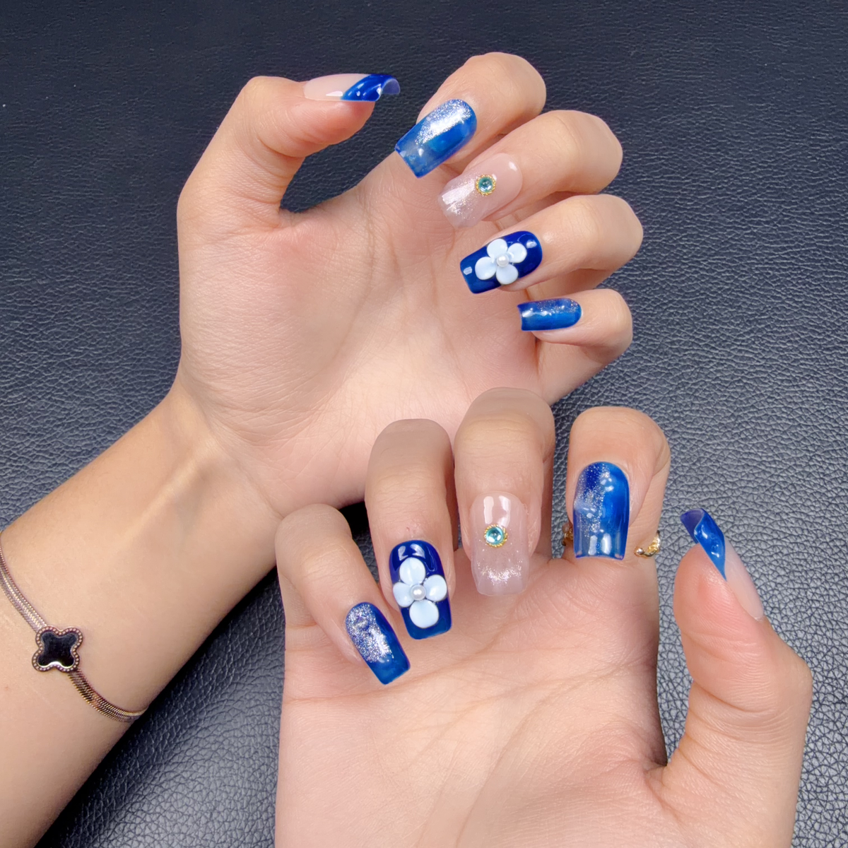Hands wearing Cobalt blue 3D floral medium square press-on nails with white flowers