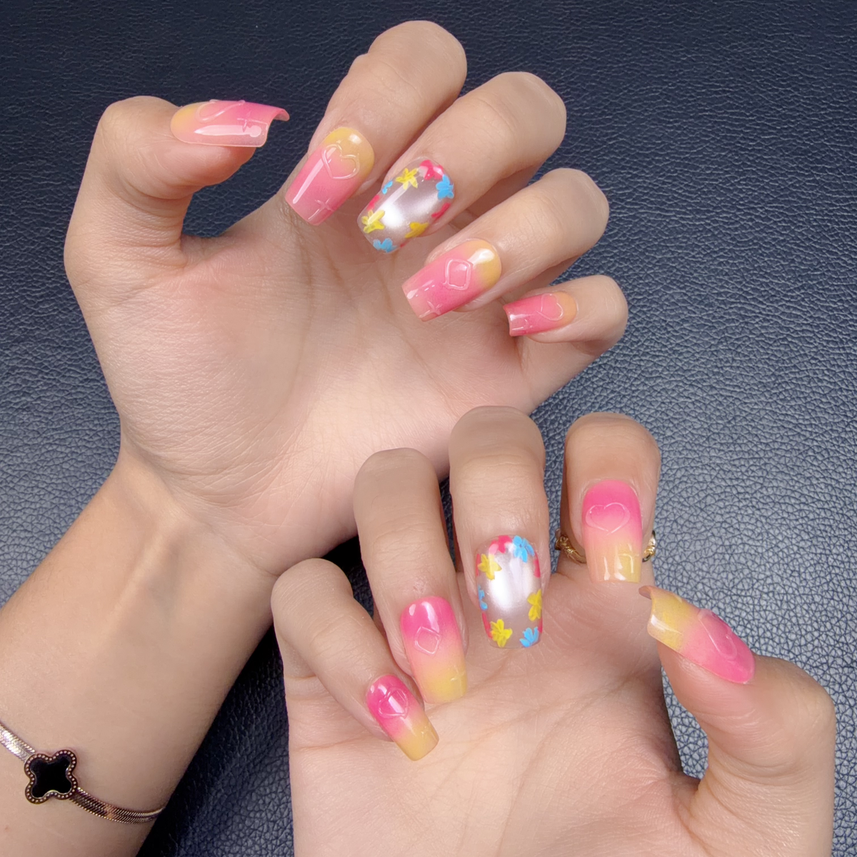 Hands wearing Sunset Pop pink and yellow ombre floral medium square press-on nails