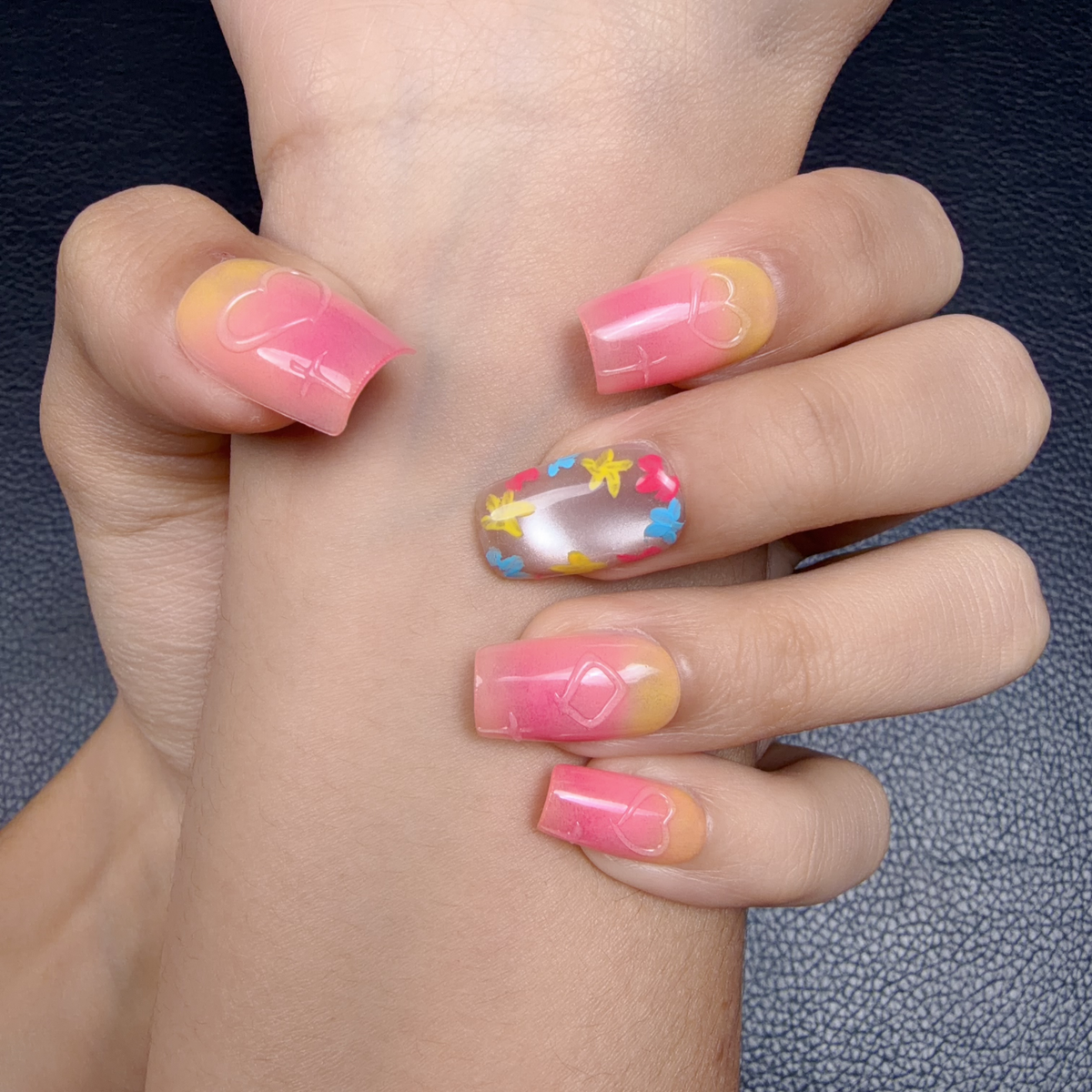Hands wearing Sunset Pop pink and yellow ombre floral medium square press-on nails
