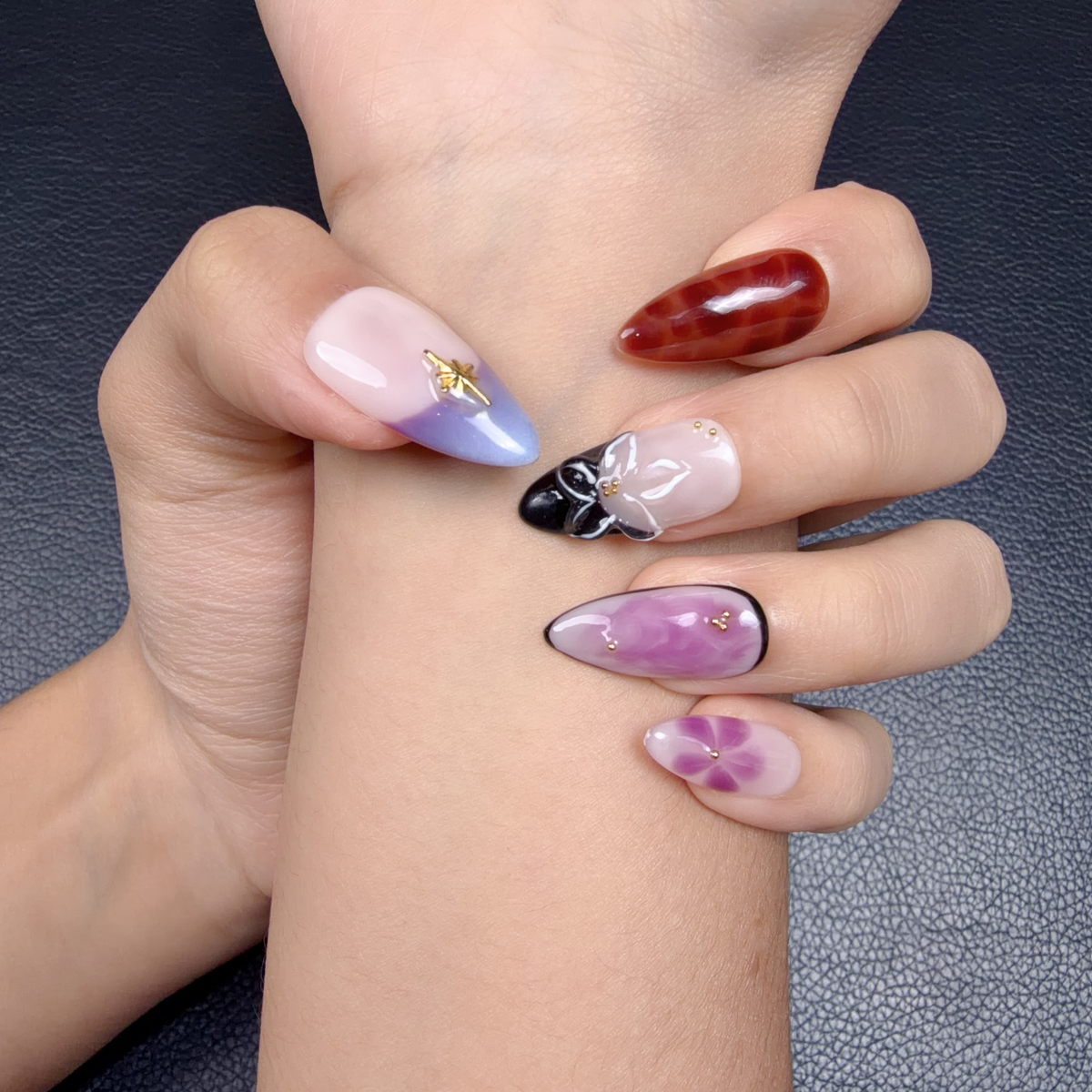 Hands wearing Violet Tortoise lavender tortoiseshell floral bow medium almond press-on nails