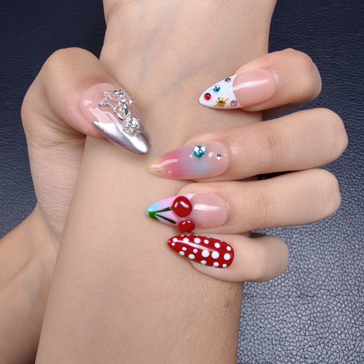 Hands wearing Cherry Rodeo red cherry and blush pink medium almond press-on nails