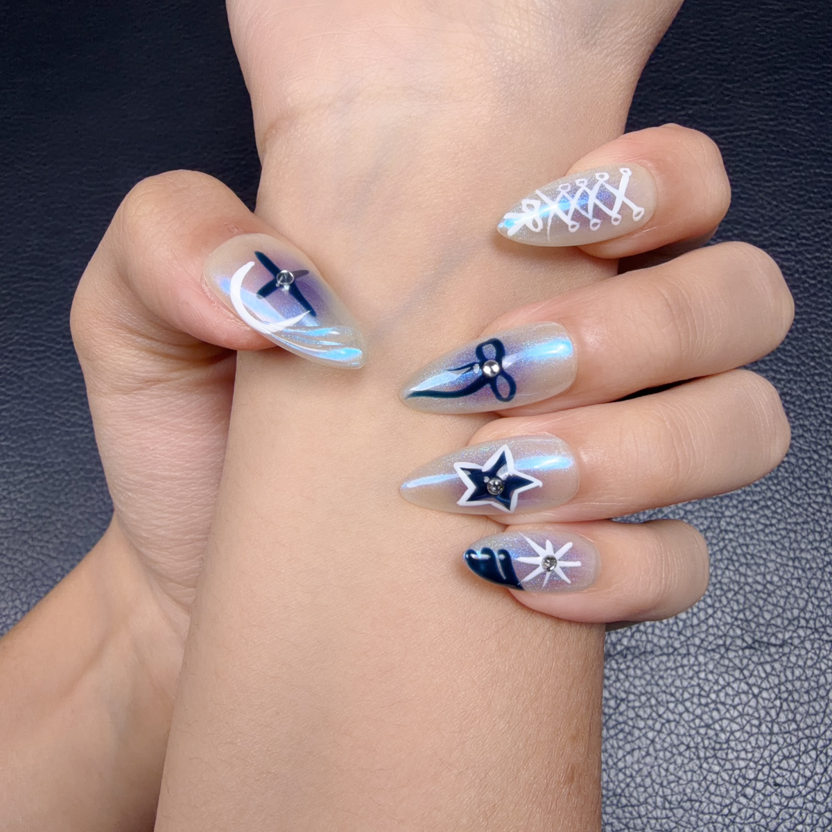 Hands wearing Blue Comet icy blue chrome celestial long almond press-on nails