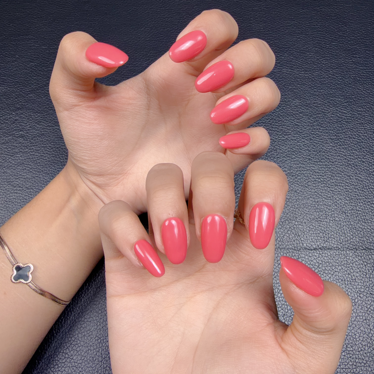 Hands wearing Coral Jelly coral pink glossy short oval press-on nails