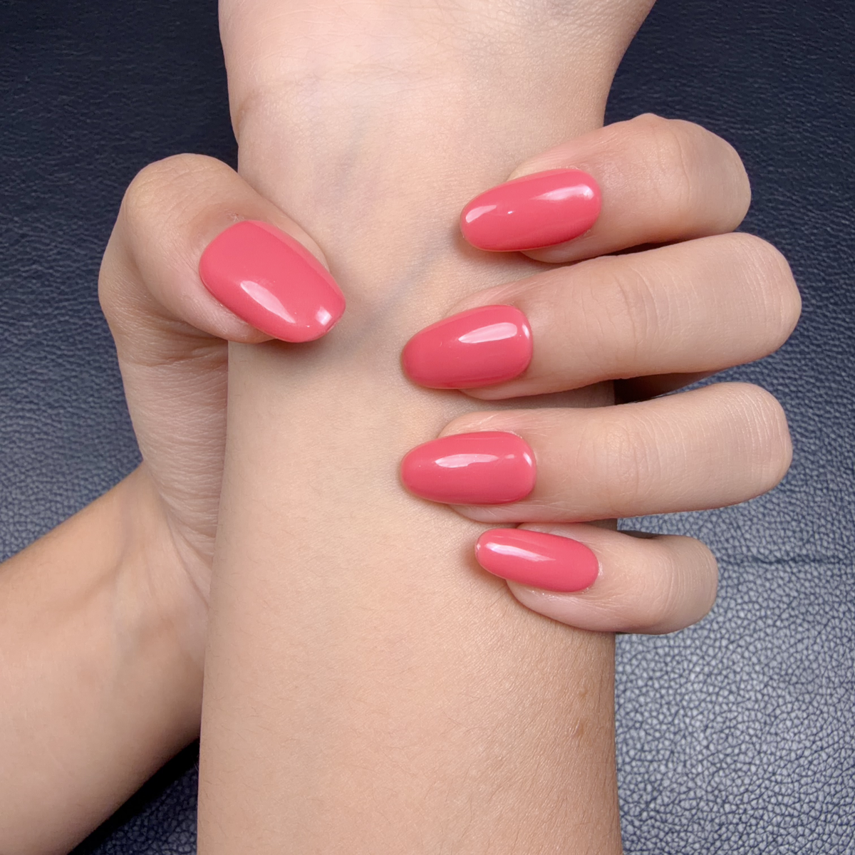 Hands wearing Coral Jelly coral pink glossy short oval press-on nails