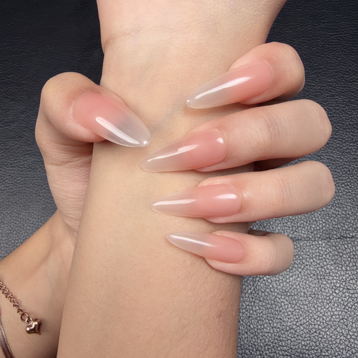Hands wearing Nude Veil peach nude to grey ombre glossy extra-long oval press-on nails