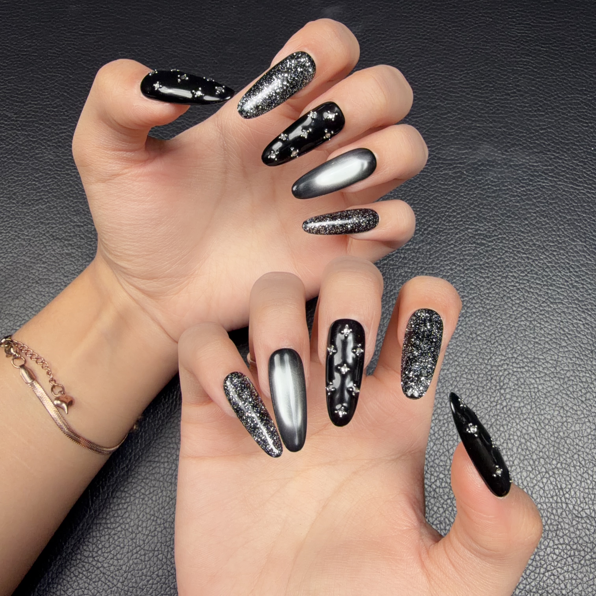 Hands wearing Midnight Shimmer black and silver cat eye crystal medium oval press-on nails