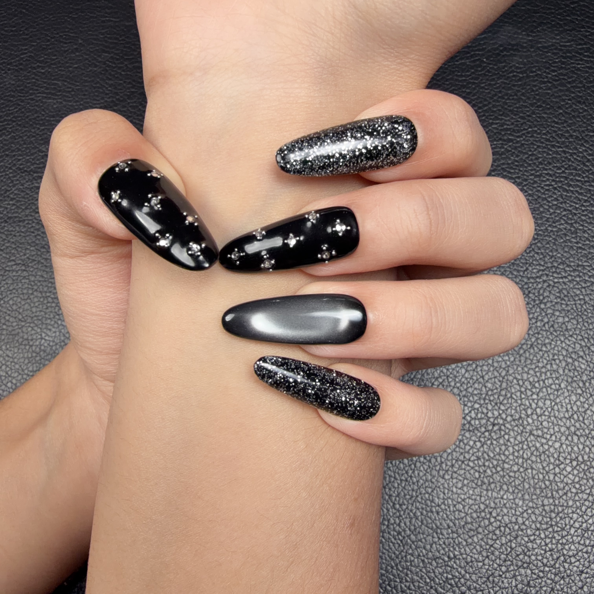 Hands wearing Midnight Shimmer black and silver cat eye crystal medium oval press-on nails