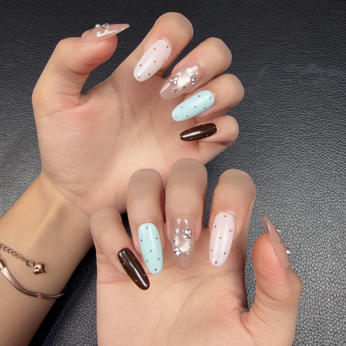 Hands wearing Pastel Galaxy pastel blue, pink and chocolate brown star medium oval press-on nails