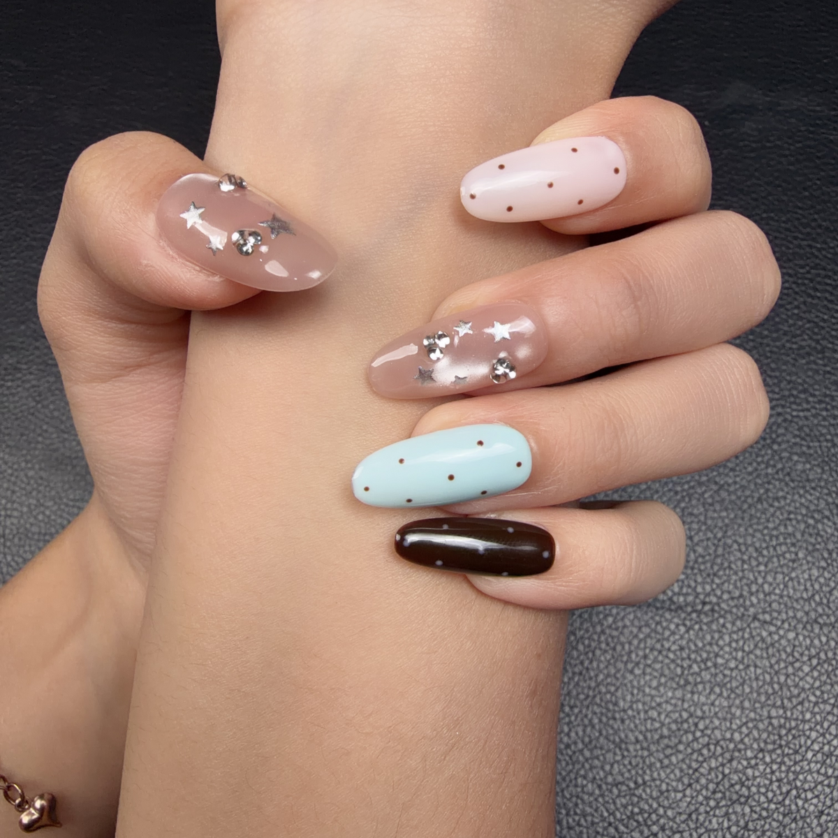 Hands wearing Pastel Galaxy pastel blue, pink and chocolate brown star medium oval press-on nails
