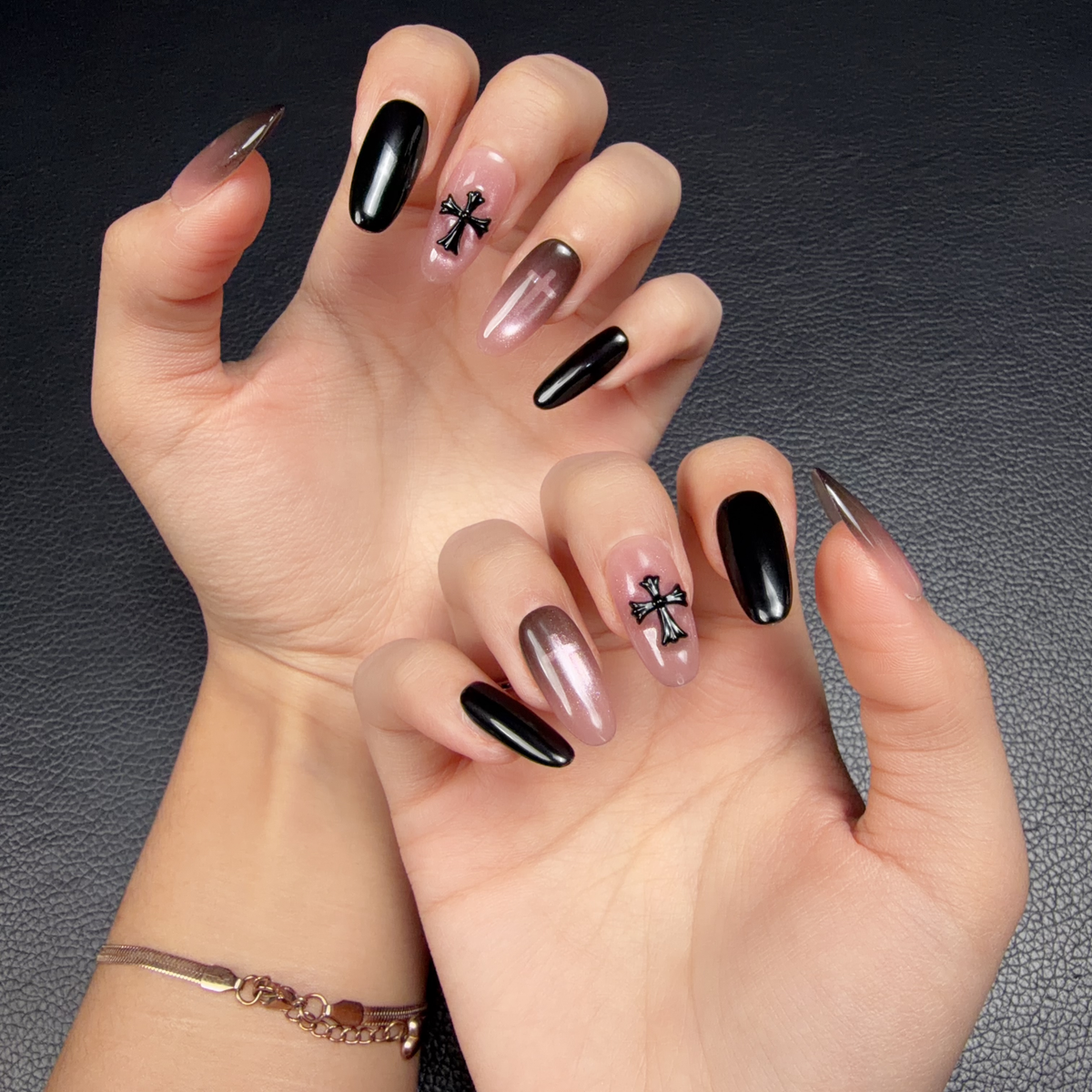 Hands wearing Shadow Cross black and smoky pink cross medium oval press-on nails