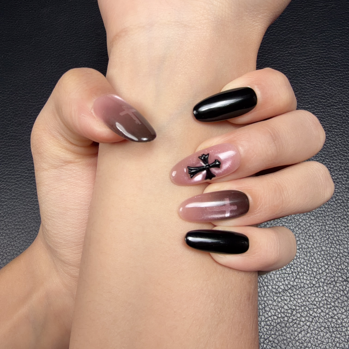 Hands wearing Shadow Cross black and smoky pink cross medium oval press-on nails