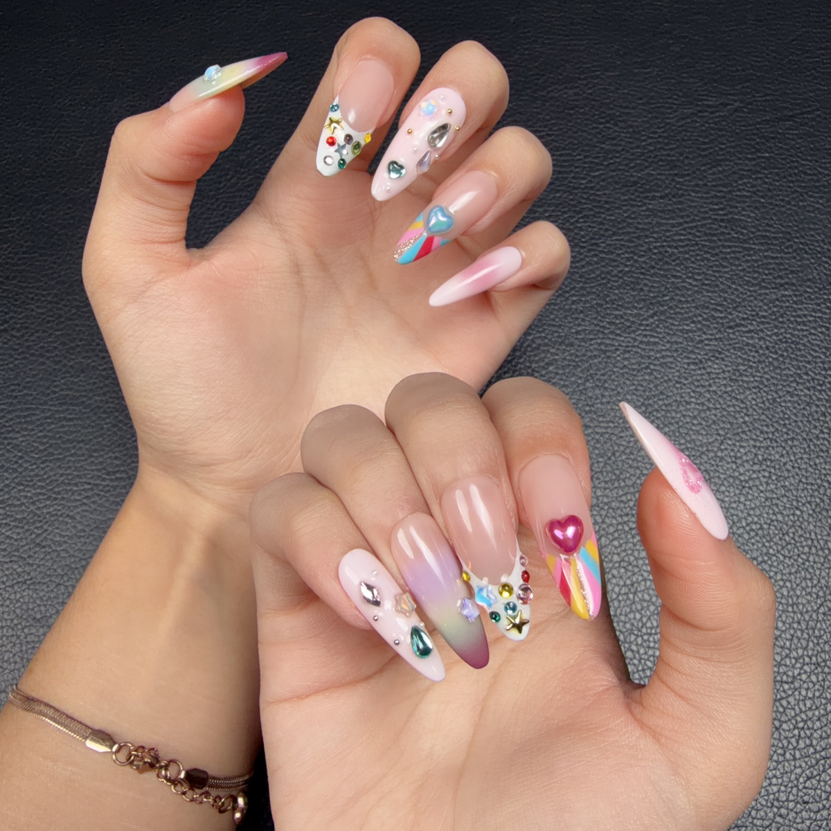 Hands wearing Sugar Pop pastel rainbow crystal heart Y2K medium almond press-on nails