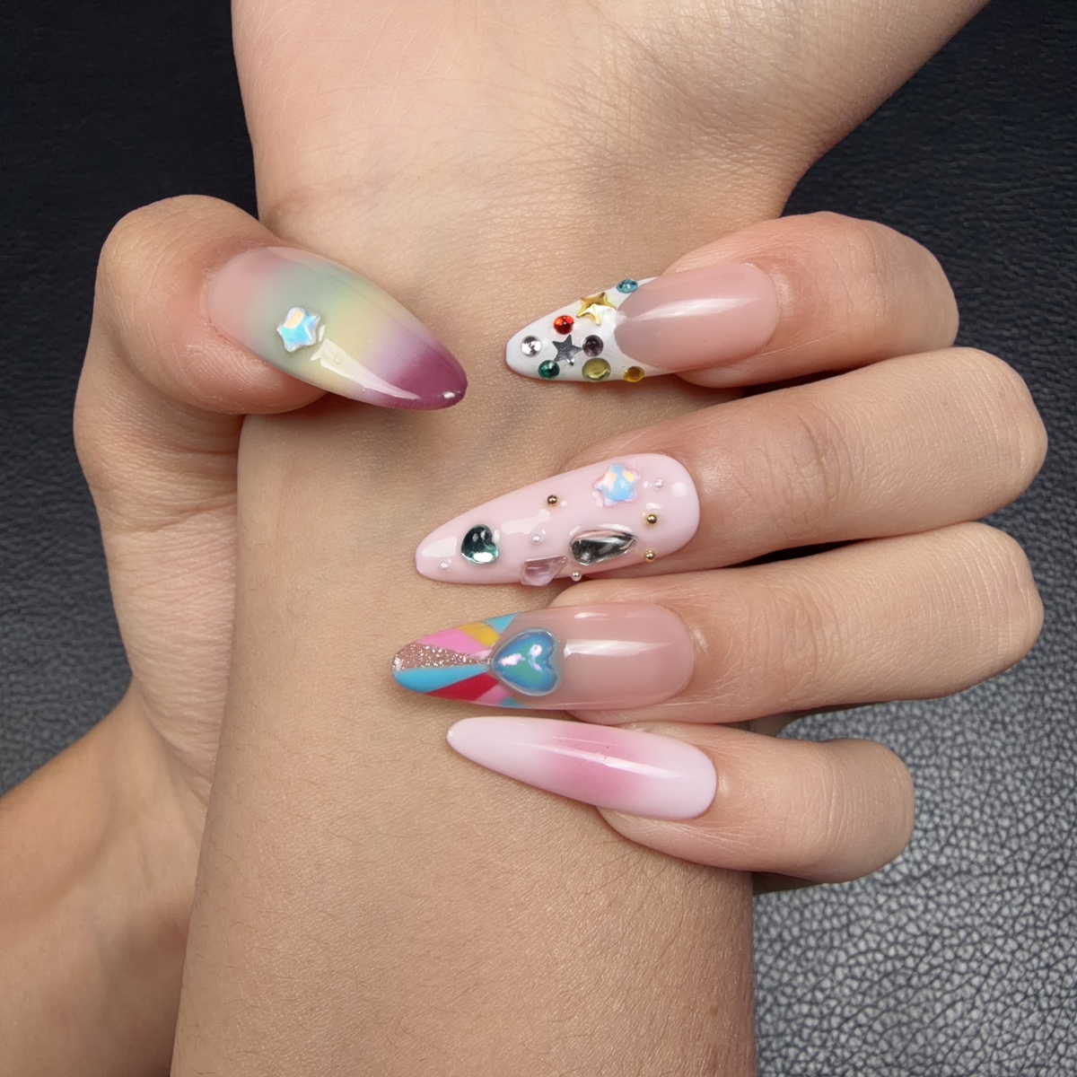Hands wearing Sugar Pop pastel rainbow crystal heart Y2K medium almond press-on nails
