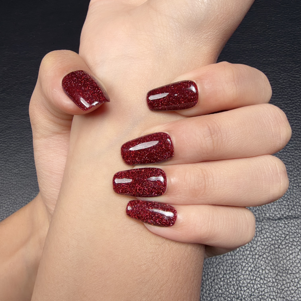 Hands wearing Scarlet Spark ruby red glitter medium square press-on nails