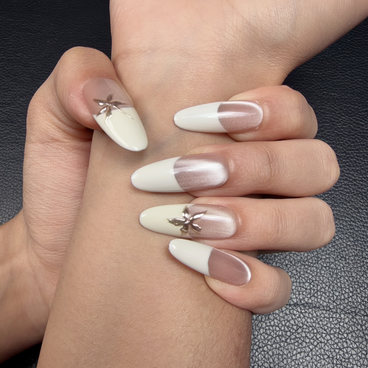 Hands wearing Ivory Star ivory French tip extra-long oval press-on nails with metallic stars