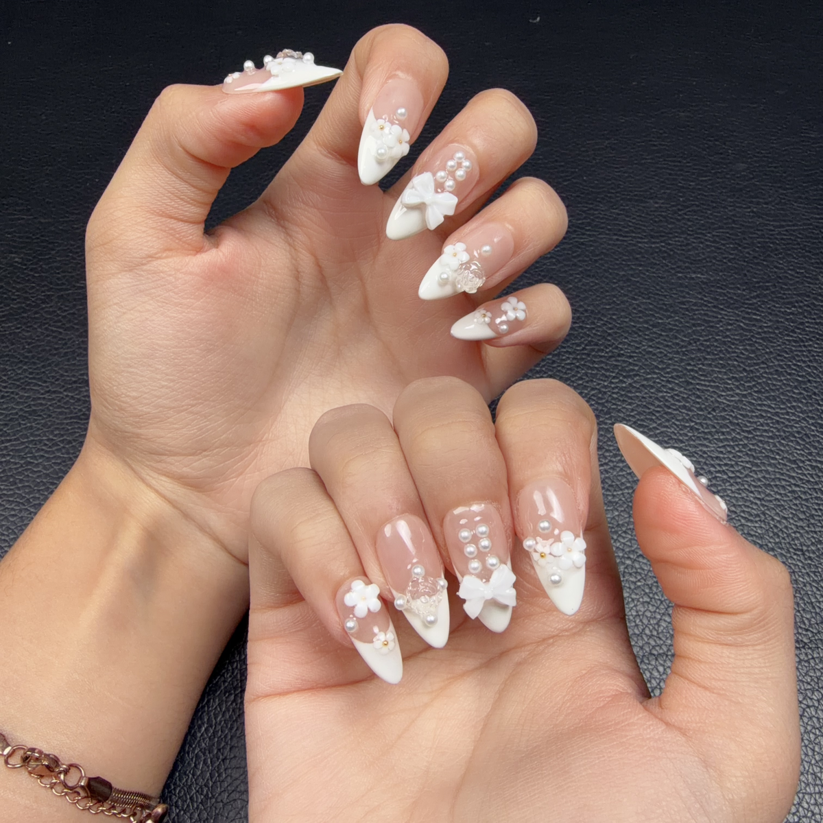 Hands wearing Pearl Bouquet white French tip floral pearl medium almond press-on nails with a bow