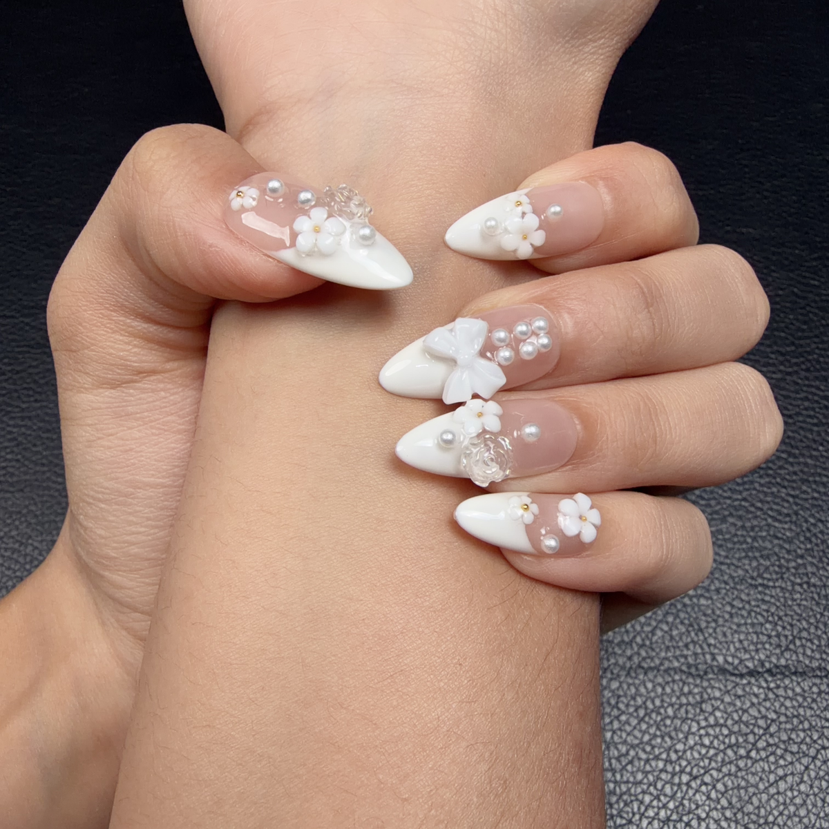 Hands wearing Pearl Bouquet white French tip floral pearl medium almond press-on nails with a bow