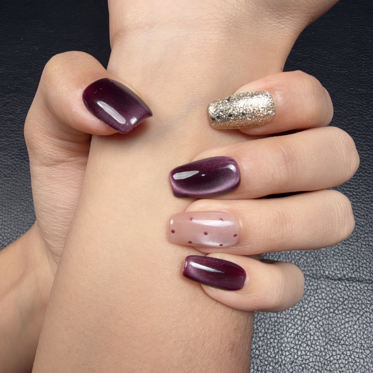 Hands wearing Burgundy cat eye gold glitter medium square press-on nails