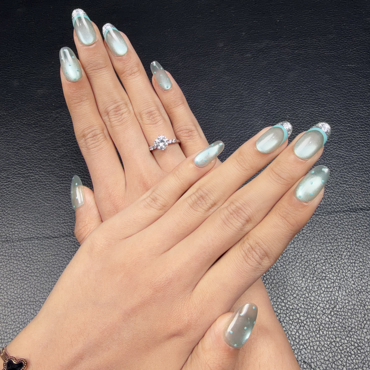 Hands wearing Ice Halo icy blue cat eye silver glitter French tip oval press-on nails