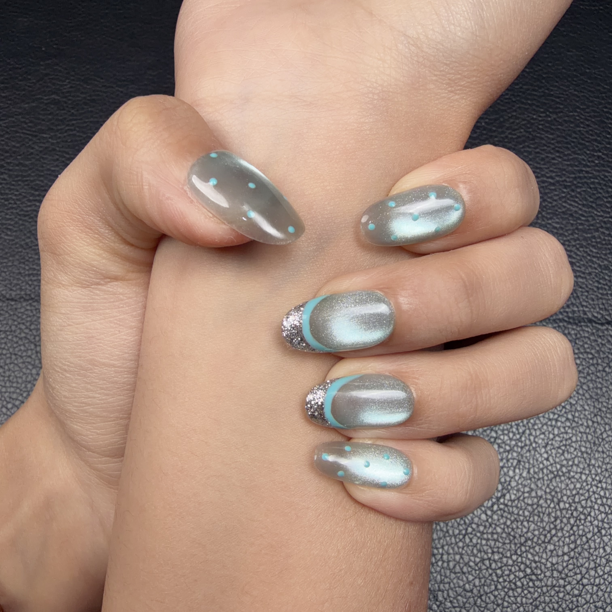Hands wearing Ice Halo icy blue cat eye silver glitter French tip oval press-on nails