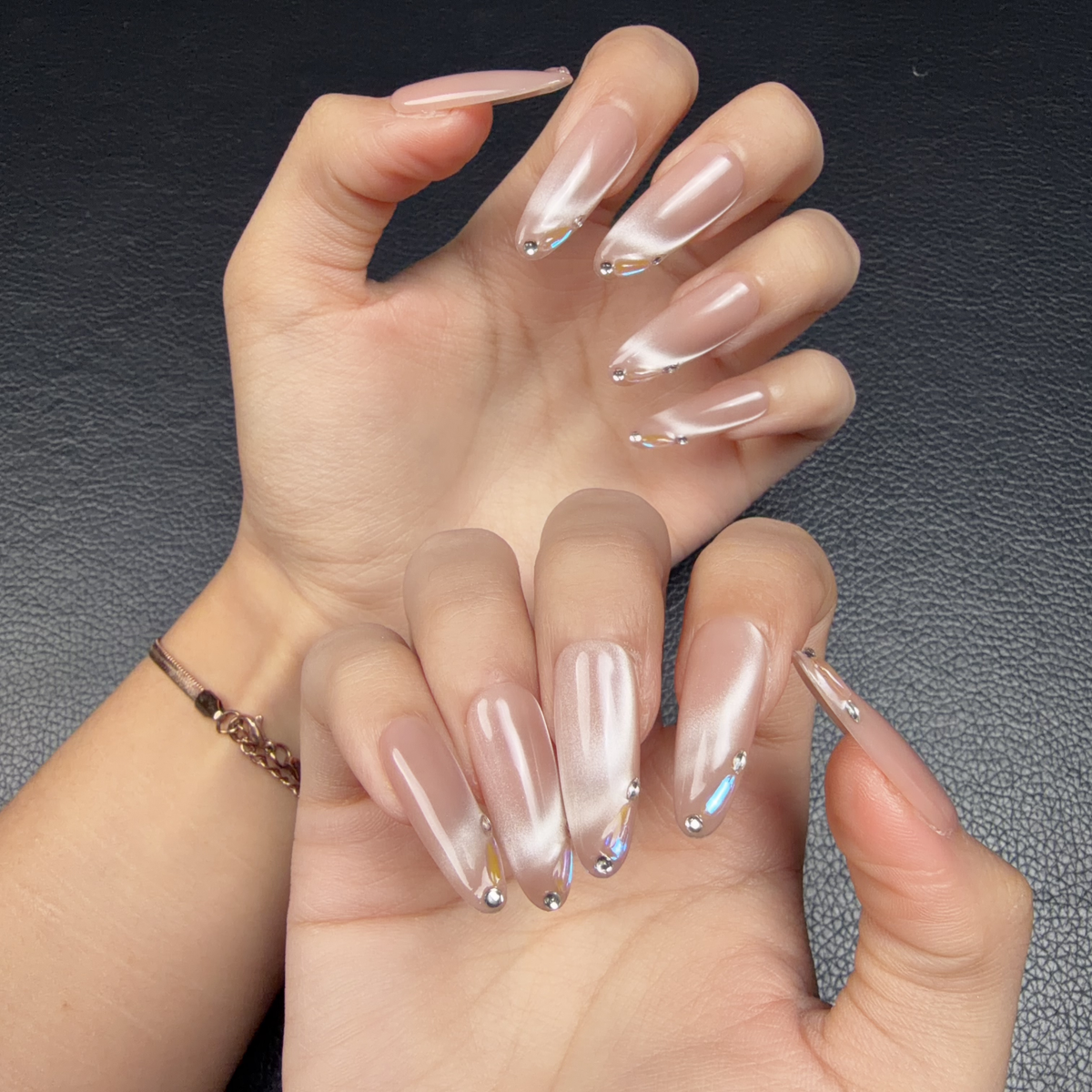 Hands wearing Nectar Prism blush pink cat eye crystal extra-long almond press-on nails